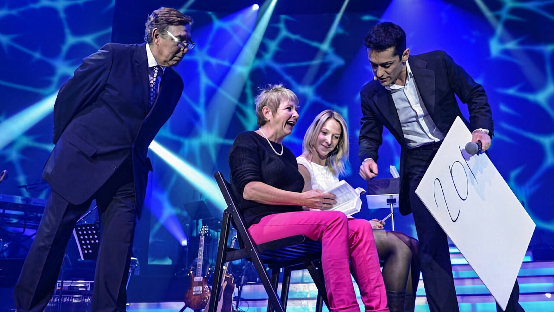 two men standing and two women sitting